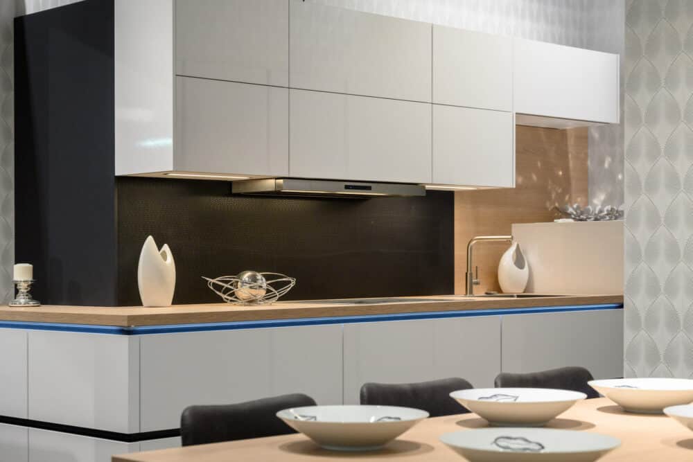 Designküche L-Form hochglanz weiß mit Griffmulden und Holz Arbeitsplatte