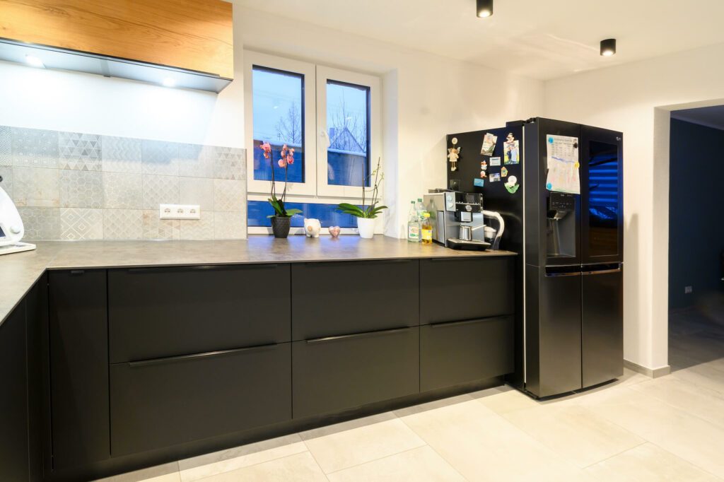 Nobilia moderne U-Küche schwarz mit Griffleisten und Standkühlschrank